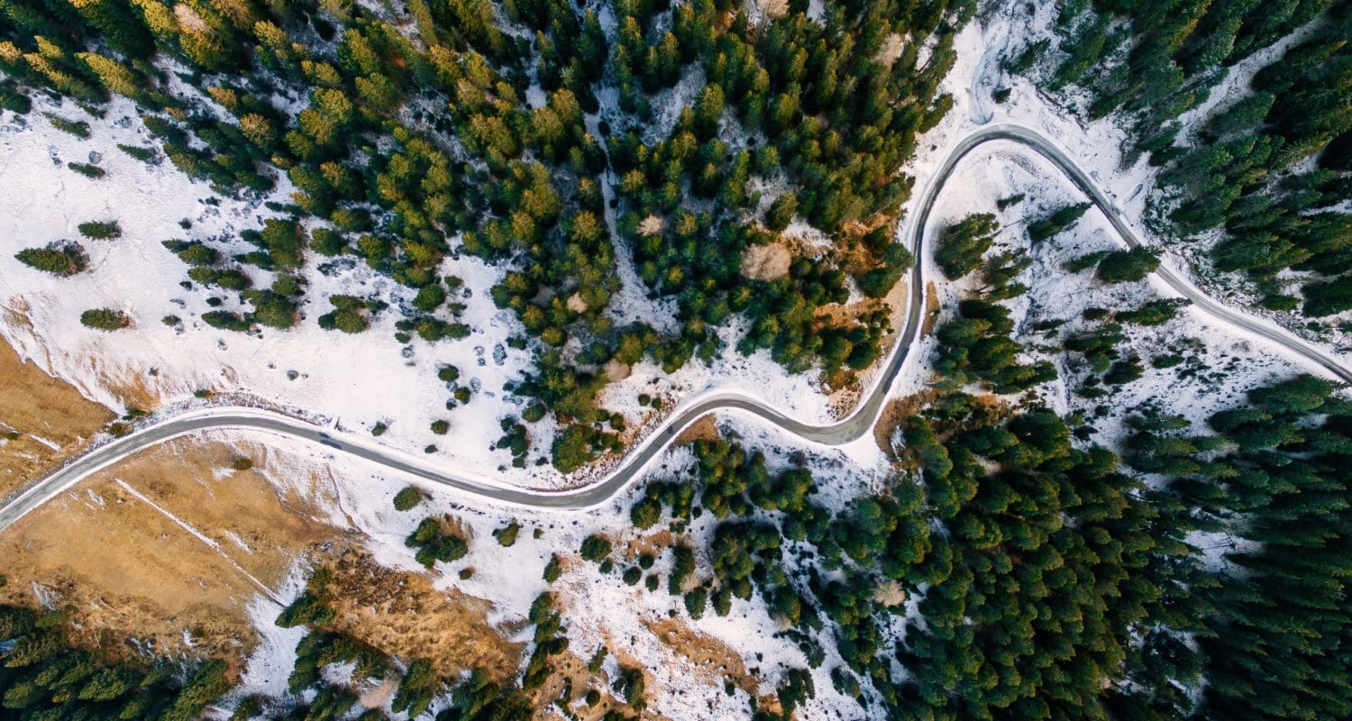 Aerial view of snowy forest with a road. Captured from above with a drone. Dolomites - Italy